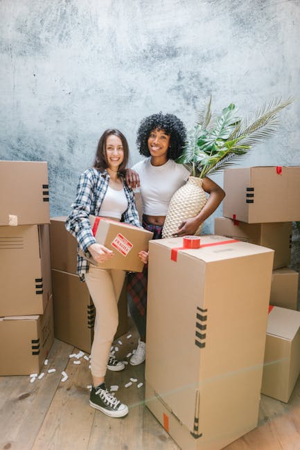 A scene inside a residential property showing a professional removals team from Removal Company Acton during a home relocation process. The image captures a removal trolley loaded with several cardboa